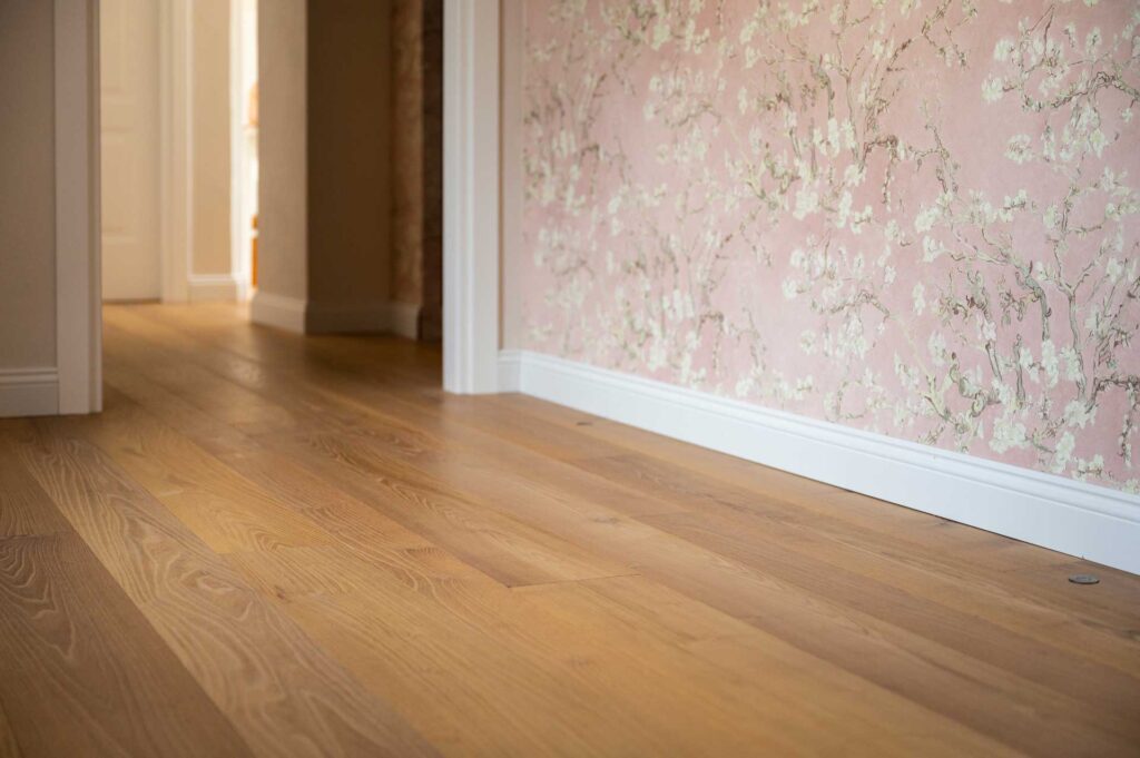 Macro di Aiace, pavimento in acacia bio in un ambiente dallo stile classico, con carta da parati a fiori.