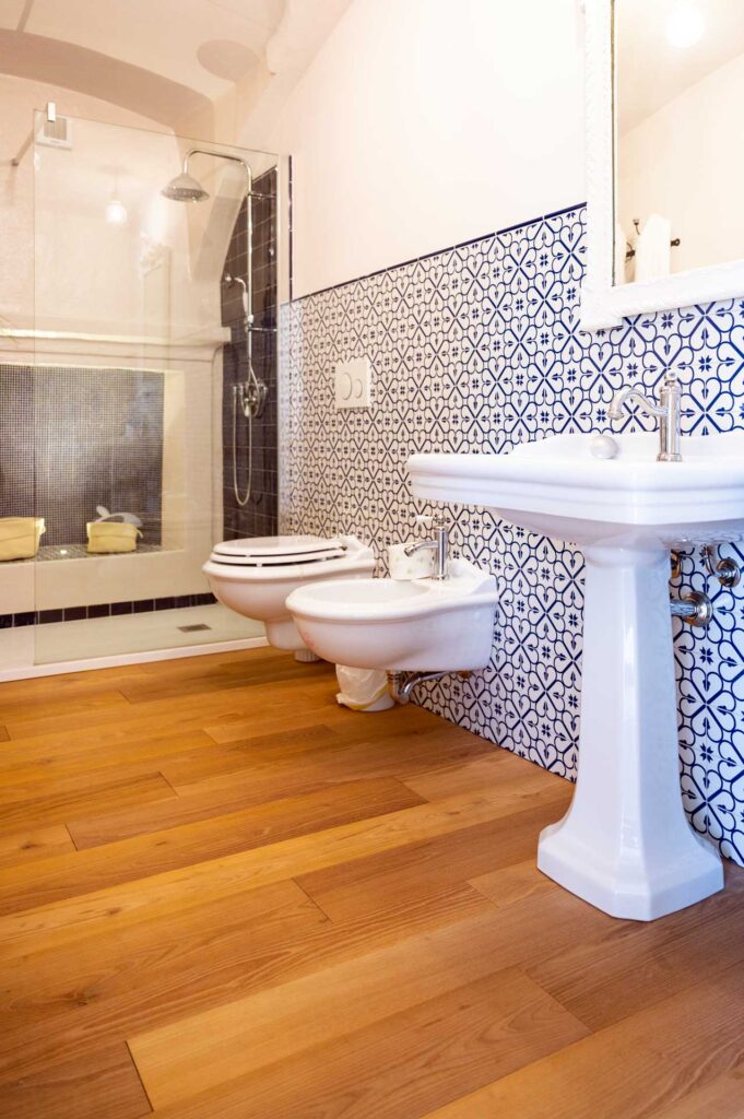 Aiace, pavimento in acacia bio in un bagno dallo stile classico, abbinato a piastrelle vintage sulle pareti, perfetto e resistente grazie alle sue vernici di alta qualità.