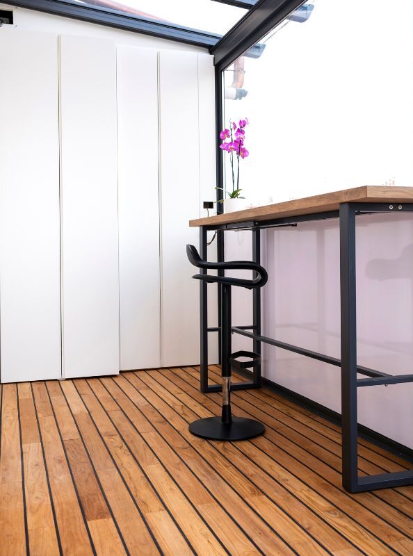 Decking in teak per una piccola area esterna chiusa con vista sulla città.