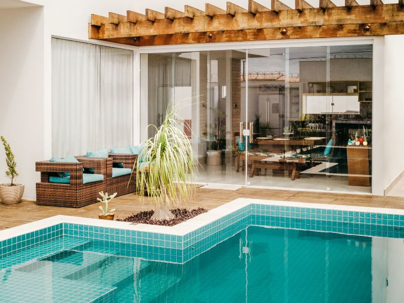 Pavimentazione in legno antiscivolo che circonda una piscina rivestita con piastrelle in ceramica blu.