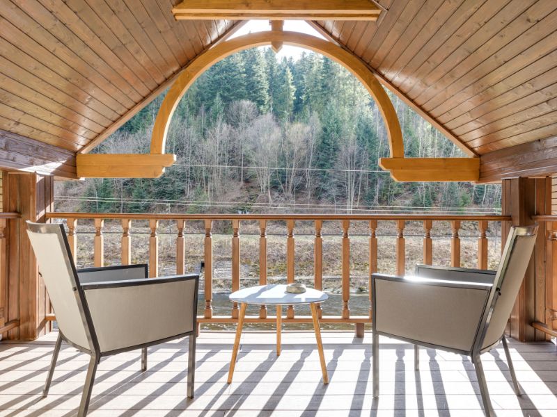 Terrazza con tettoia in legno affacciata su un bosco di abeti.